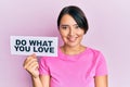 Beautiful young woman with short hair holding paper with do what you love text looking positive and happy standing and smiling Royalty Free Stock Photo