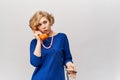 A beautiful young woman with short wavy blond hair in a classic blue dress holds a retro handset from her phone Royalty Free Stock Photo