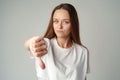 Beautiful young woman showing thumbs down sign to dislike on gray background Royalty Free Stock Photo