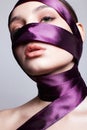 Beautiful young woman in silk ribbon on her face