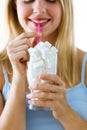 Beautiful young woman simulating to drink sugar in a glass cup over white background.