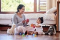 Beautiful young woman and single mother playing toy blocks with her adorable little baby daughter in the bedroom at home Royalty Free Stock Photo