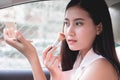 Beautiful young woman sit in car on driver`s seat looking at the mirror checking, brushing make up Royalty Free Stock Photo