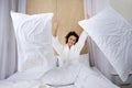 Beautiful young woman sits on the bed and throws a pillow at home having fun, Having fun on weekend at home Royalty Free Stock Photo