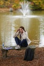 Beautiful young woman sits on college campus in fall alone Royalty Free Stock Photo