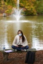 Beautiful young woman sits on college campus in fall alone wearing mask Royalty Free Stock Photo