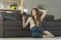 Beautiful young woman sits on living room floor and takes video or selfie. Teen girl makes stories.Girl with smart phone Royalty Free Stock Photo