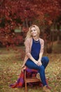 Beautiful young woman sits in park in the fall