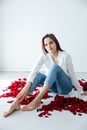 beautiful woman sits among the red rose flower petals Royalty Free Stock Photo