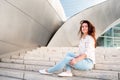 A beautiful young woman sits on the steps of the Walt Disney Concert Hall. Popular destination for sightseeing in Los Angeles