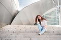 A beautiful young woman sits on the steps of the Walt Disney Concert Hall. Popular destination for sightseeing in Los Angeles