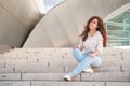 A beautiful young woman sits on the steps of the Walt Disney Concert Hall. Popular destination for sightseeing in Los Angeles