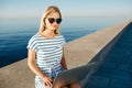 Beautiful young woman sitting on beach with laptop smiling and c Royalty Free Stock Photo