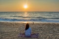 Beautiful young woman sitting on the beach near ocean during sunset Royalty Free Stock Photo