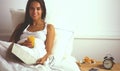 Beautiful young woman sitting in bed and having breakfast Royalty Free Stock Photo