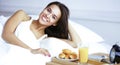 Beautiful young woman sitting in bed and having breakfast Royalty Free Stock Photo