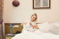 Beautiful young woman sitting on bed and having breakfast Royalty Free Stock Photo