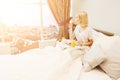 Beautiful young woman sitting on bed and having breakfast Royalty Free Stock Photo