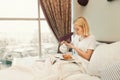 Beautiful young woman sitting on bed and having breakfast Royalty Free Stock Photo