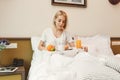 Beautiful young woman sitting on bed and having breakfast Royalty Free Stock Photo