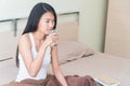 Young woman sitting in bed holding a glass of water to drink Royalty Free Stock Photo