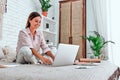 Beautiful young woman sitting on bed, working Royalty Free Stock Photo