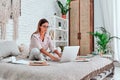 Beautiful young woman sitting on bed, working Royalty Free Stock Photo