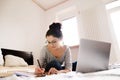 Beautiful young woman sitting on bed, working. Home office. Royalty Free Stock Photo