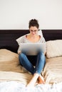 Beautiful young woman sitting on bed, working. Home office. Royalty Free Stock Photo