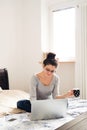 Beautiful young woman sitting on bed, working. Home office. Royalty Free Stock Photo