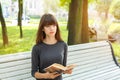 Beautiful young woman sitting on a bench in the street reading a book Royalty Free Stock Photo