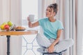 Beautiful young woman sitting on a chair next to the window. Having a fresh croissant and a glass of orange juice for Royalty Free Stock Photo