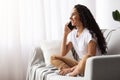 Beautiful young woman sitting on couch, talking on phone Royalty Free Stock Photo