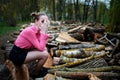 Beautiful young woman sitting and covering his face with his hands, on stack of felled tree trunks in the forest Royalty Free Stock Photo