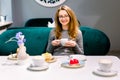 Beautiful young woman sitting and drinking coffee or tea. Closeup of pretty blond young woman sitting at the table with Royalty Free Stock Photo