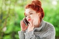 Beautiful young woman sitting in the garden having a conversation on her cell phone Royalty Free Stock Photo