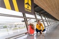 Beautiful young woman sitting on the ground waiting at the airport with her luggage. Royalty Free Stock Photo