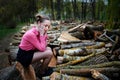 Beautiful young woman sitting and holding his head with his hands, on stack of felled tree trunks in the forest Royalty Free Stock Photo