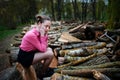 Beautiful young woman sitting and holding his head with his hands, on stack of felled tree trunks in the forest Royalty Free Stock Photo