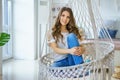 Beautiful young woman sitting in a knitted hammock happy Royalty Free Stock Photo