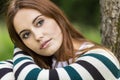 Beautiful Young Woman Sitting Leaning Against Tree