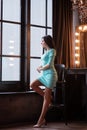 Beautiful young woman sitting near dressing table at home. Beautiful brunette in a dress Royalty Free Stock Photo