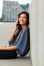 Beautiful young woman sitting outdoors and talking on cell phone Royalty Free Stock Photo