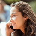 Beautiful young woman sitting outside having a conversation on her cell phone Royalty Free Stock Photo