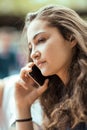 Beautiful young woman sitting outside having a conversation on her cell phone Royalty Free Stock Photo