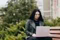 Beautiful young woman sitting in public park chatting over laptop computer. Royalty Free Stock Photo