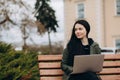 Beautiful young woman sitting in public park chatting over laptop computer Royalty Free Stock Photo