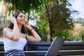 Beautiful young woman sitting in public park working on laptop computer Royalty Free Stock Photo