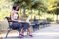 Beautiful young woman sitting in public park working on laptop computer Royalty Free Stock Photo
