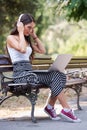 Beautiful young woman sitting in public park working on laptop computer Royalty Free Stock Photo